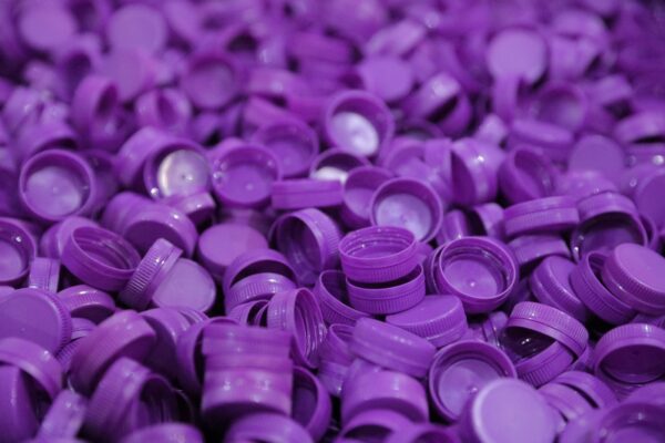 A close up of numerous purple plastic bottle caps scattered together 