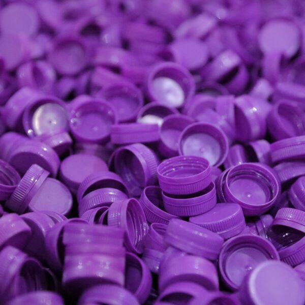 A close up of numerous purple plastic bottle caps scattered together 