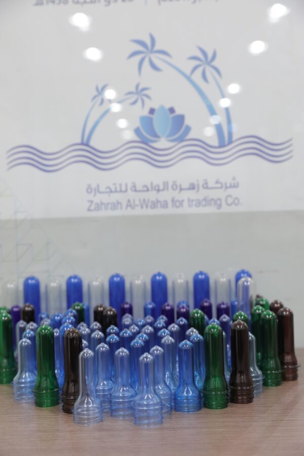 A collection of colorful plastic bottle caps arranged in a pattern, with a company logo in the background 
