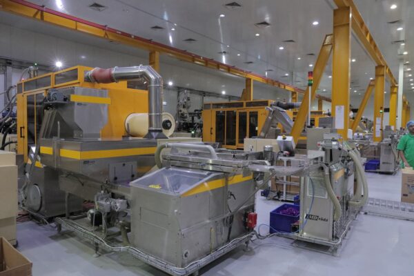 A modern industrial facility featuring large machinery, conveyor belts, and a worker in a green shirt 