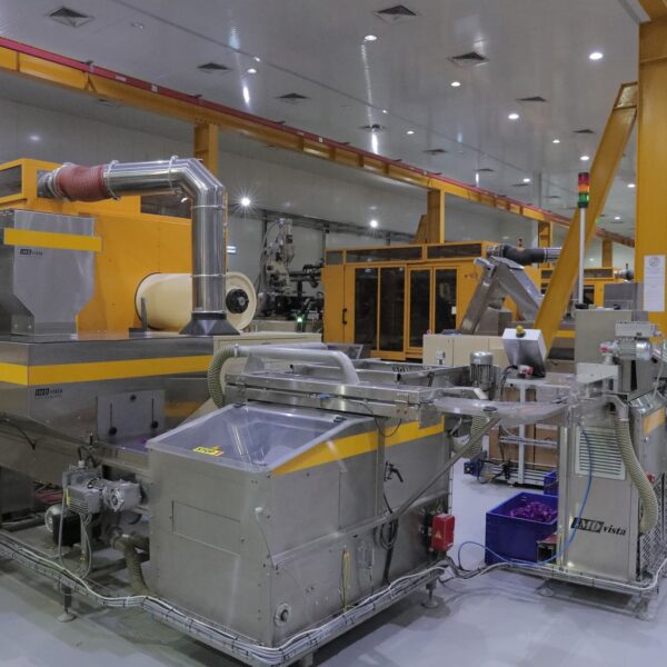 A modern industrial facility featuring large machinery, conveyor belts, and a worker in a green shirt 